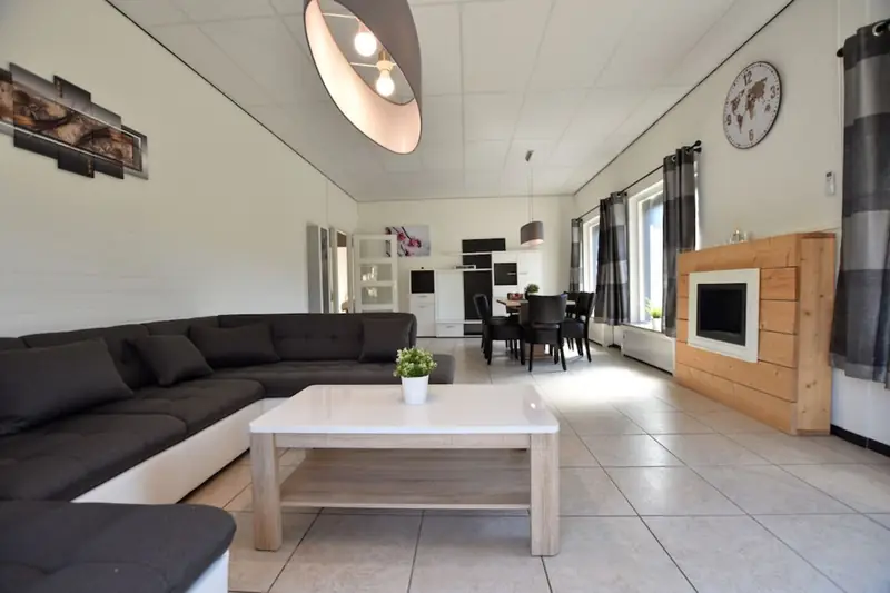 Lange woonkamer met hoekbank en salontafel, met de eethoek aan het eind.